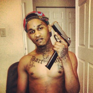 Fredo Santana posing with a pistol in hand.